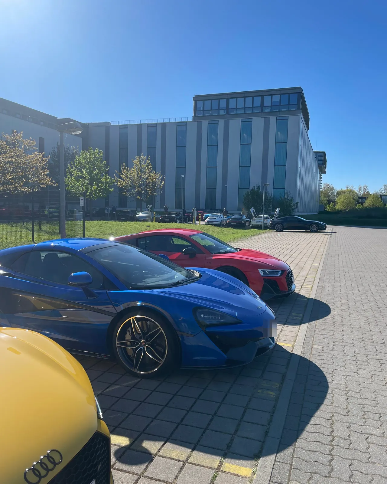 Sportwagen in einer Reihe auf dem Parkplatz beim Season Opening, vorn ein blauer McLaren