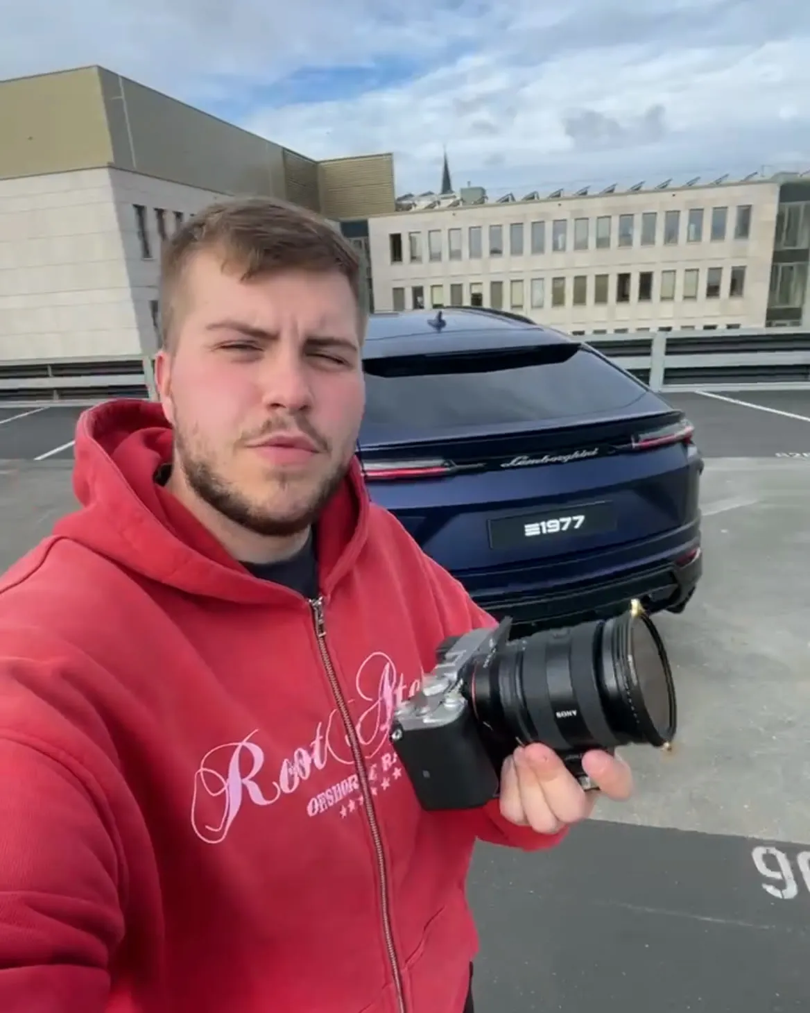 Selfie mit Kamera vor dem Heck des Urus auf dem Parkdeck