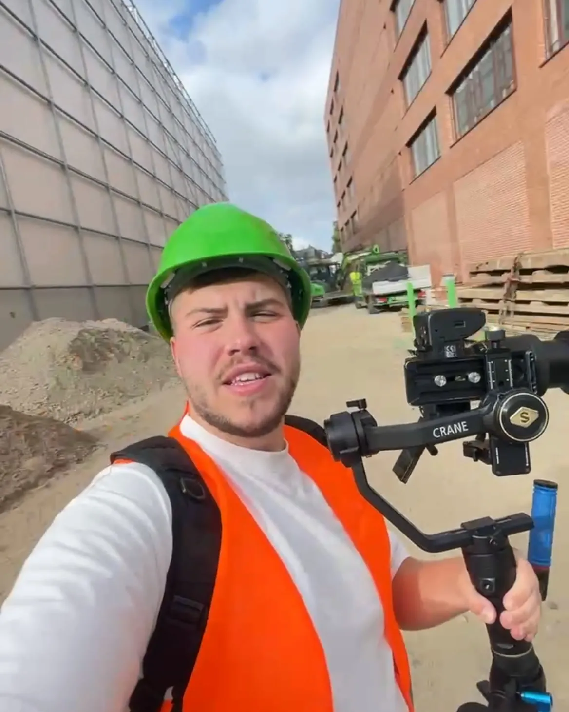 Selfie mit Helm und Warnweste auf der Baustelle, in der Hand der Gimbal