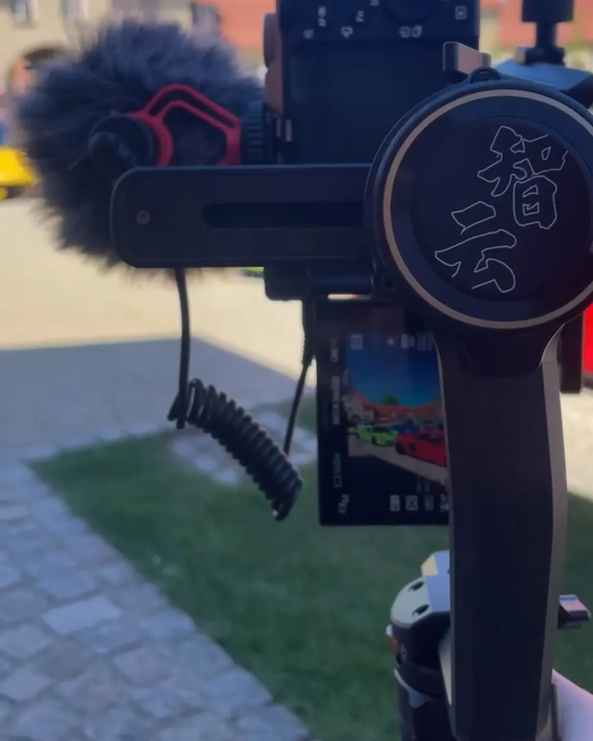 Kamera mit Mikrofon auf dem Gimbal, auf dem Bildschirm die Sportwagen beim Dreh
