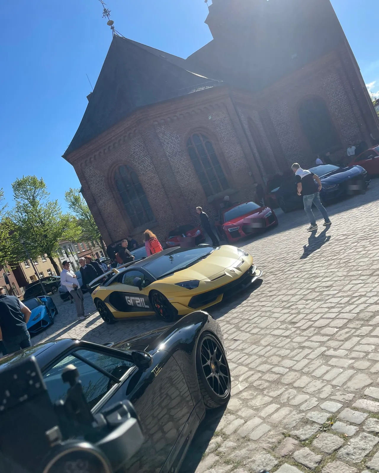 Sportwagen auf Kopfsteinpflaster vor einer alten Backsteinkirche